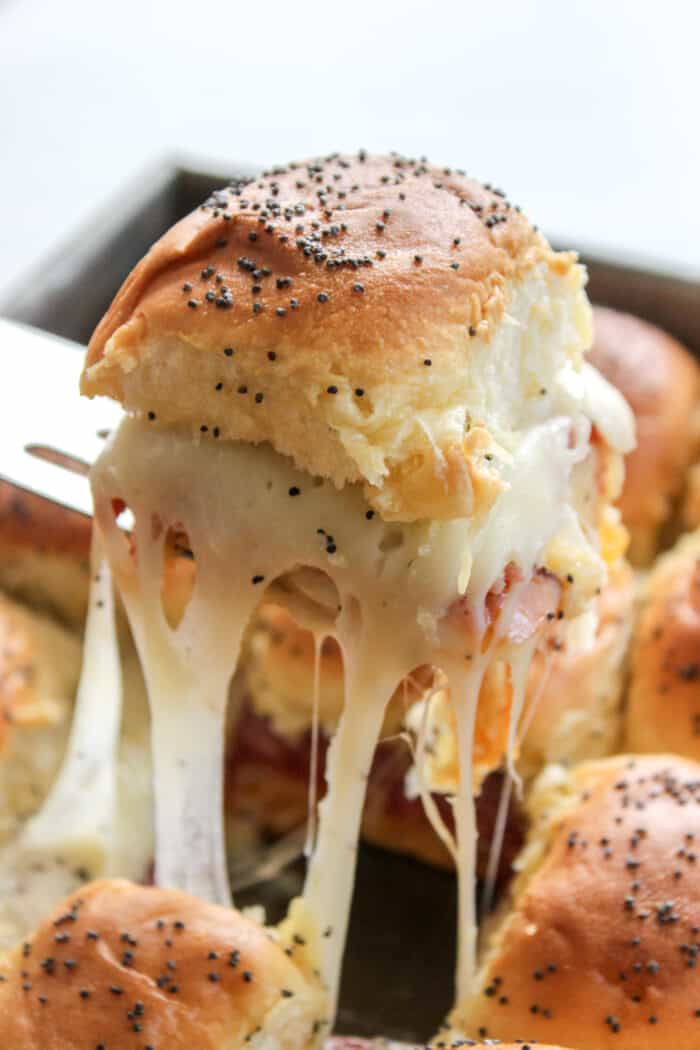 Italian Sliders in a pan with one being pulled out to show the melted cheese