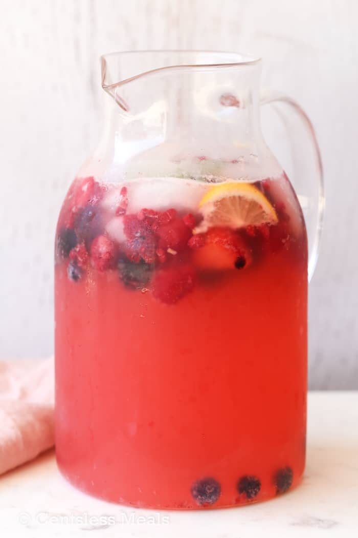 Lemonade in a juice pitcher with berries and lemons