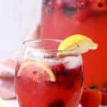 Lemonade in a glass with berries and lemon wedges