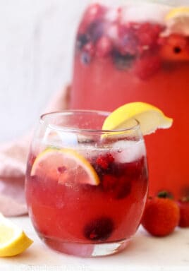 Lemonade in a glass with berries and lemon wedges