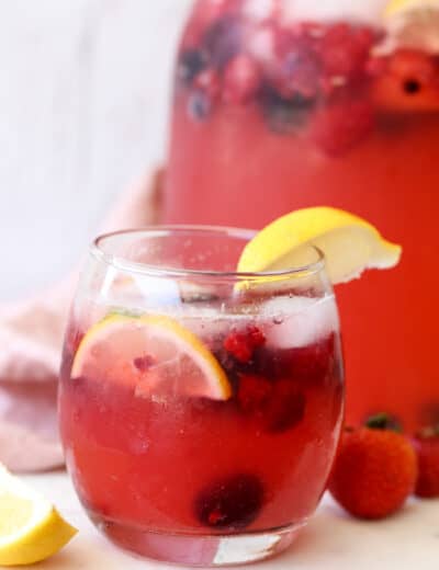 Lemonade in a glass with berries and lemon wedges