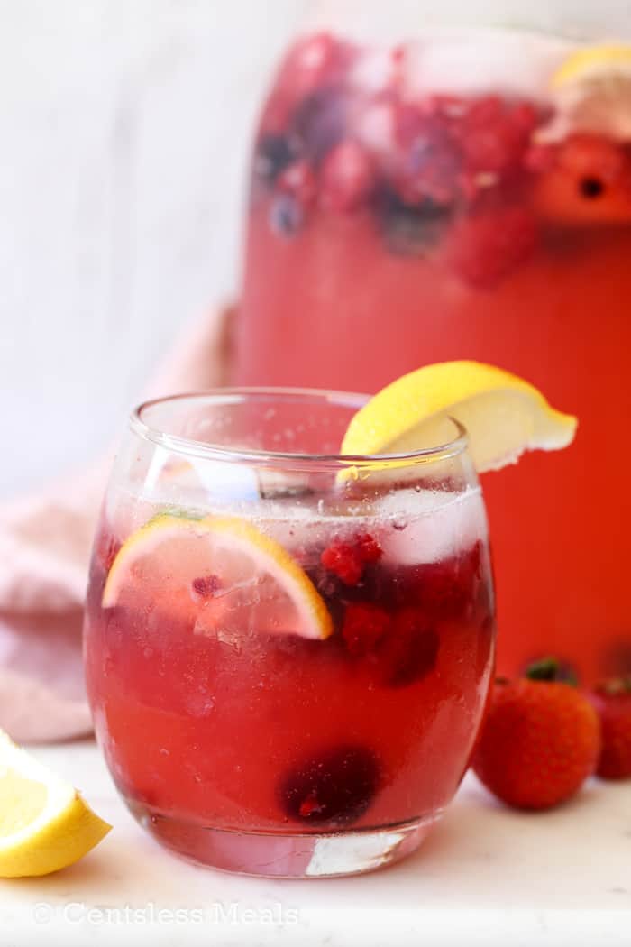 Lemonade in a glass with berries and lemon wedges