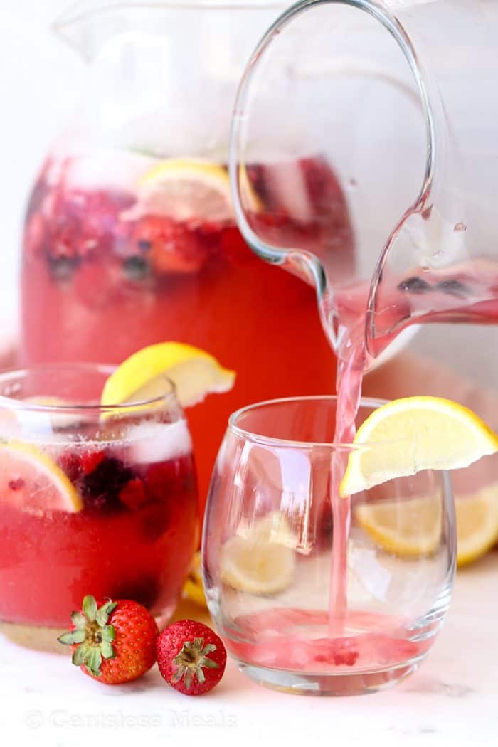 Lemonade in glasses being poured from a jug