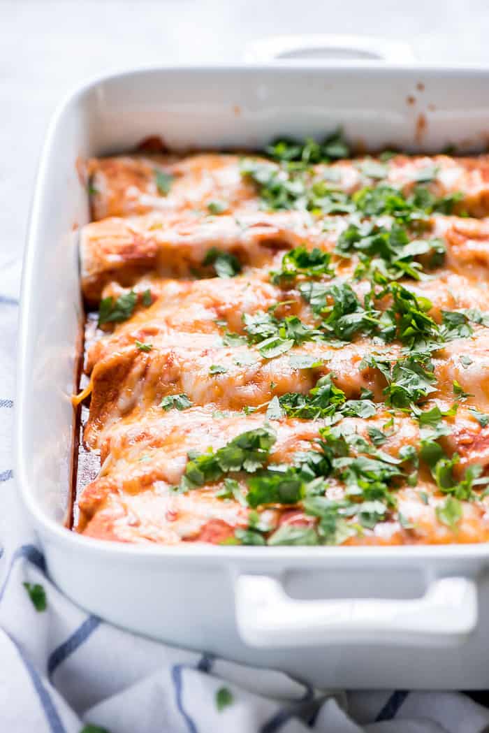 Beef enchiladas in a white casserole dish garnished with cilantro