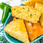 Jalapeno cornbread in a blue bowl with jalapenos on the side