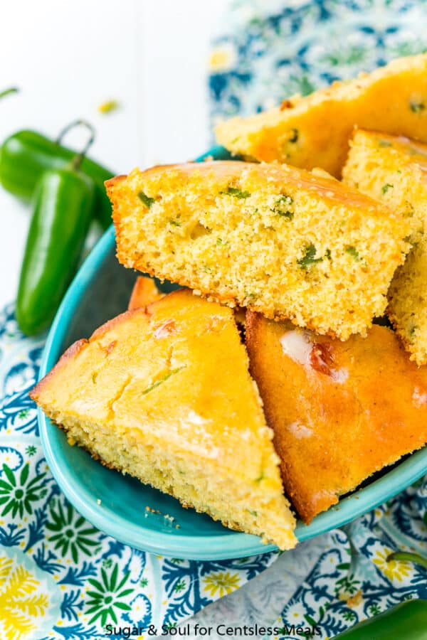 Jalapeno cornbread in a blue bowl with jalapenos on the side