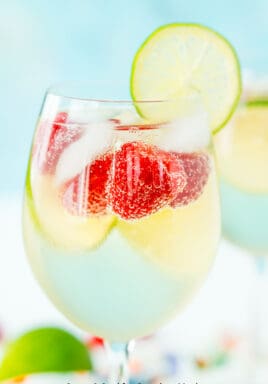 Raspberry lime wine spritzer with berries and lime as garnish