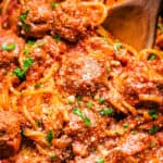 spaghetti and meatballs in a crock pot with a spoon