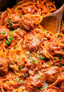 spaghetti and meatballs in a crock pot with a spoon