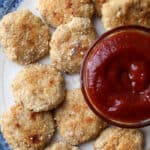 Homemade chicken nuggets on a plate with a bowl of ketchup