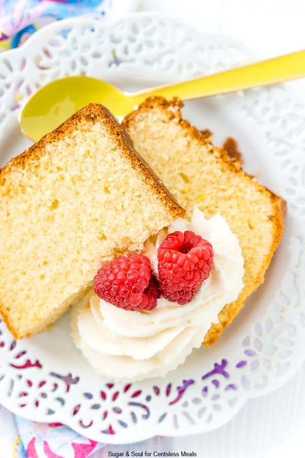 Almond pound cake on a white plate with raspberries and icing