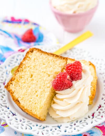 Almond pound cake on a white plate with icing and raspberries
