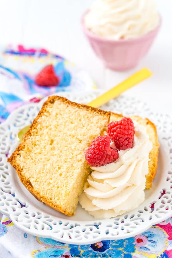 Almond pound cake on a white plate with icing and raspberries