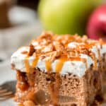 Caramel apple poke cake drizzled with caramel on a white plate