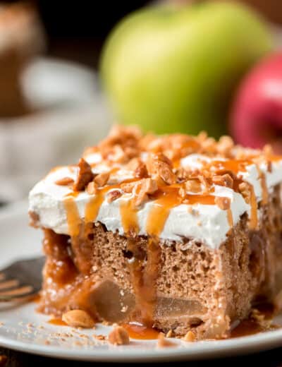 Caramel apple poke cake drizzled with caramel on a white plate