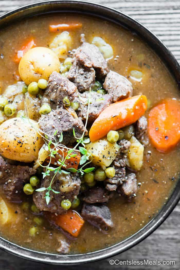 bowl of beef stew garnished with thyme