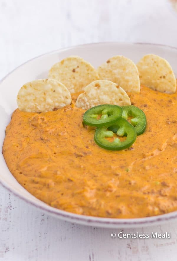 Chili cheese dip in a bowl with jalapenos and tortilla chips
