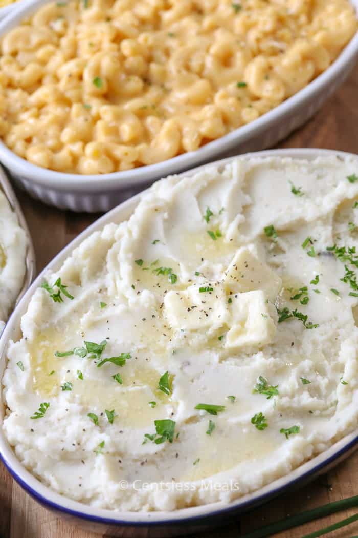 Mashed potatoes with parsley and butter and mac and cheese in a casserole dish