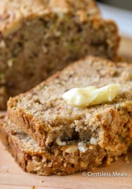 Slices of zucchini bread with melted butter and a bite taken out of 1