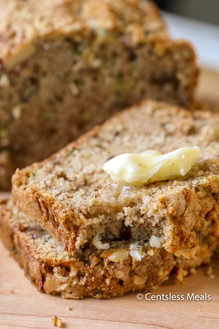 Slices of zucchini bread with melted butter and a bite taken out of 1