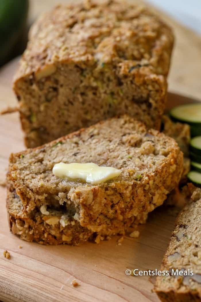 Slices of zucchini bread with melted butter on a wooden cutting board