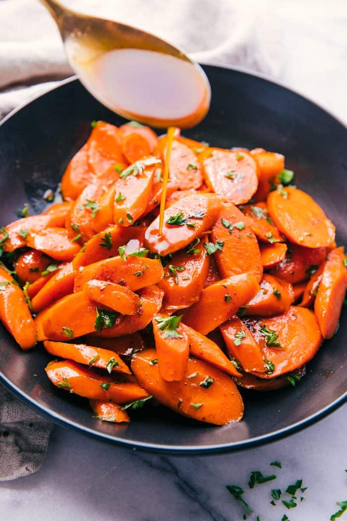 Candied carrots in a bowl with a spoon and parsley