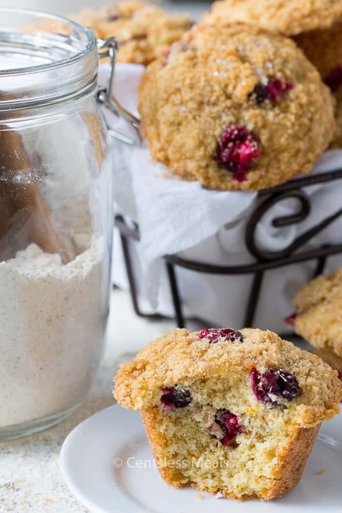Cranberry orange muffins in a basket and on a plate with a jar of muffin mix on the side