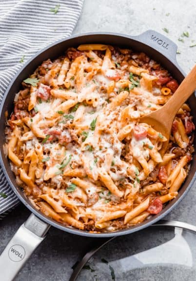 Italian sausage pasta being served out of a skillet.