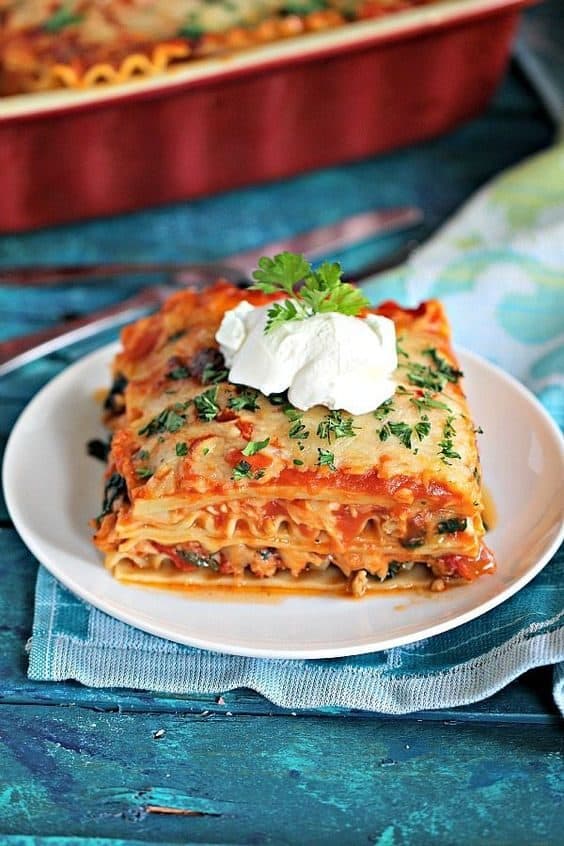 chicken spinach lasagna on a plate with a dollop of sour cream