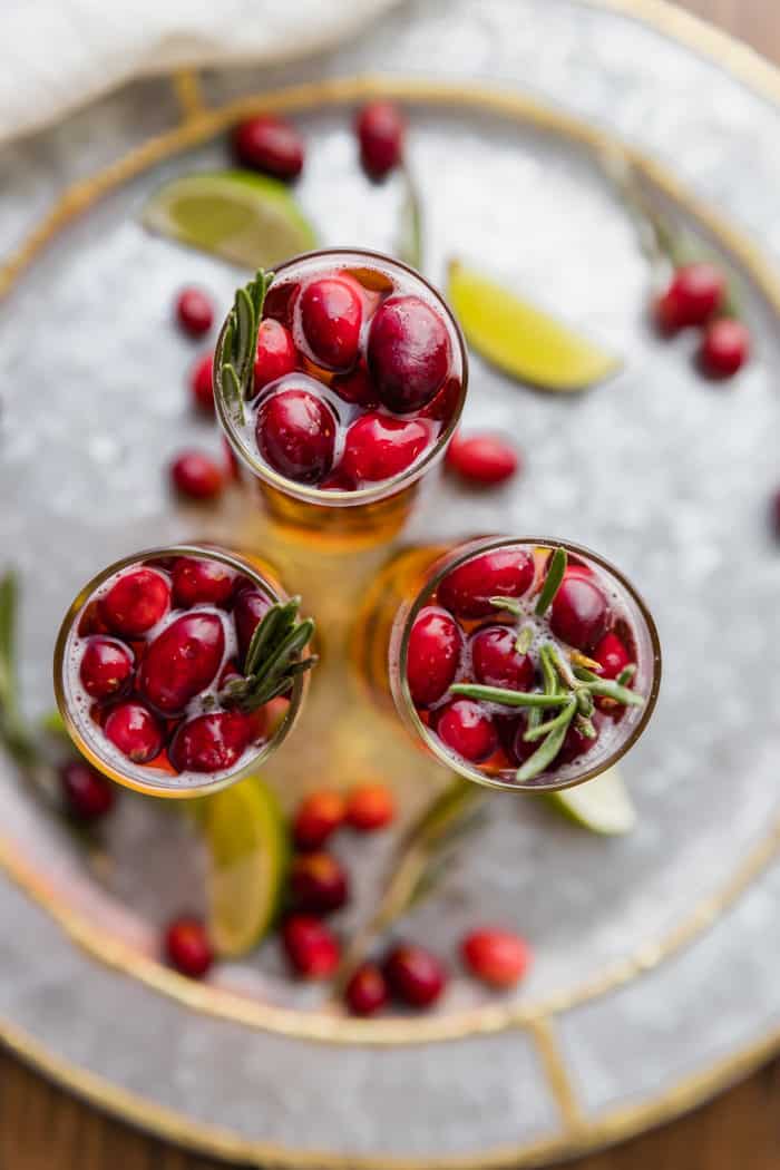 3 cranberry champagne cocktails all garnished with rosemary and cranberries