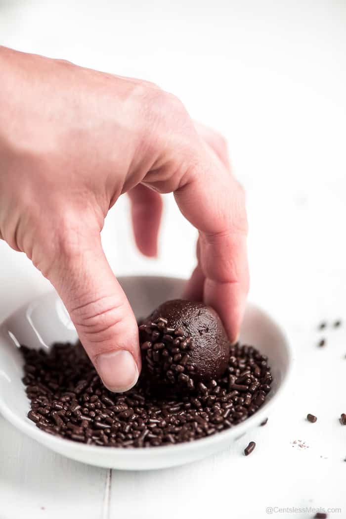 Chocolate truffle being dipped into sprinkles