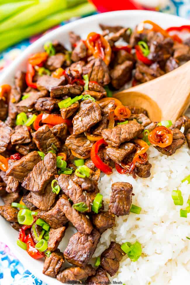 Pepper steak in a bowl with rice garnished with green onions