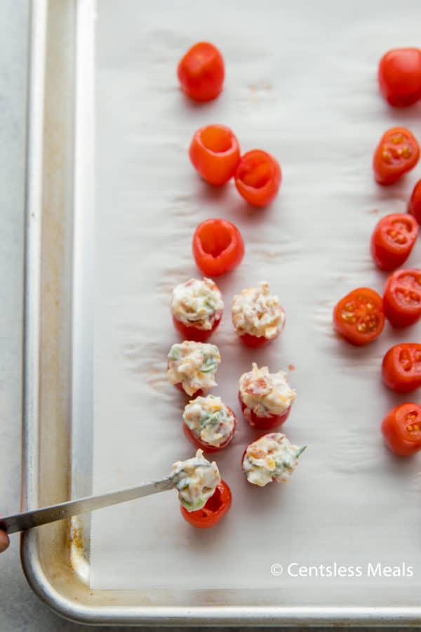 Tomatoes with a Mayo mixture on a baking sheet