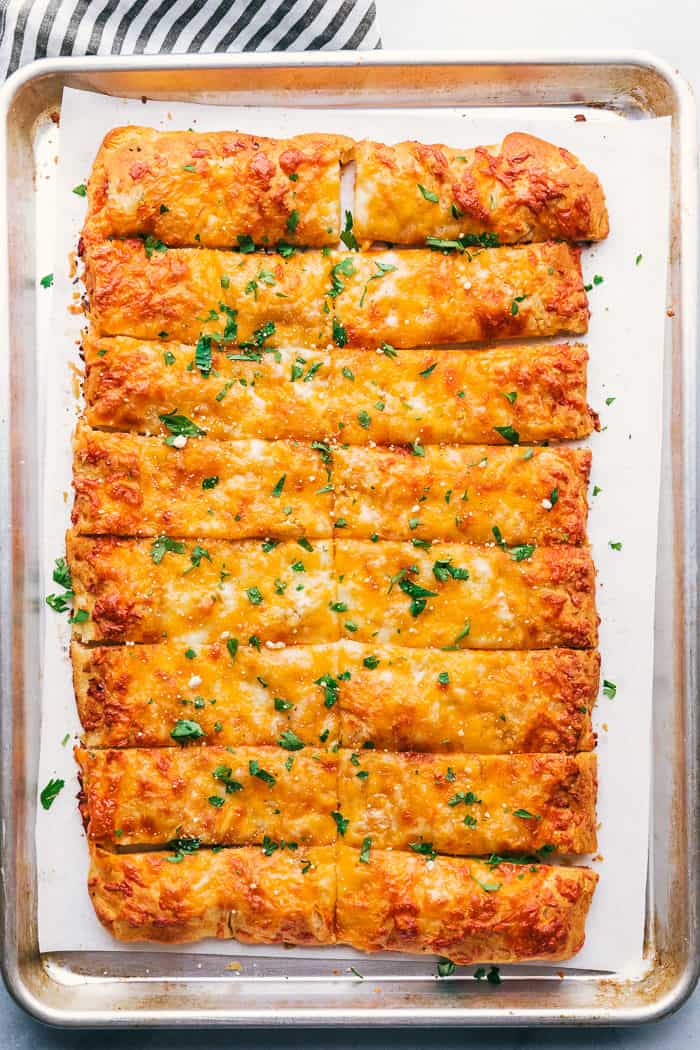 Cheesy breadsticks on a sheet pan with parsley