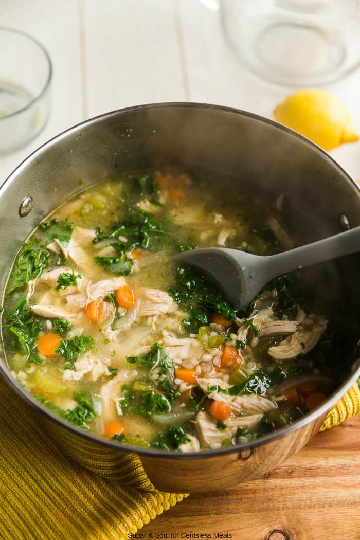 Chicken kale soup in a pot with a spoon