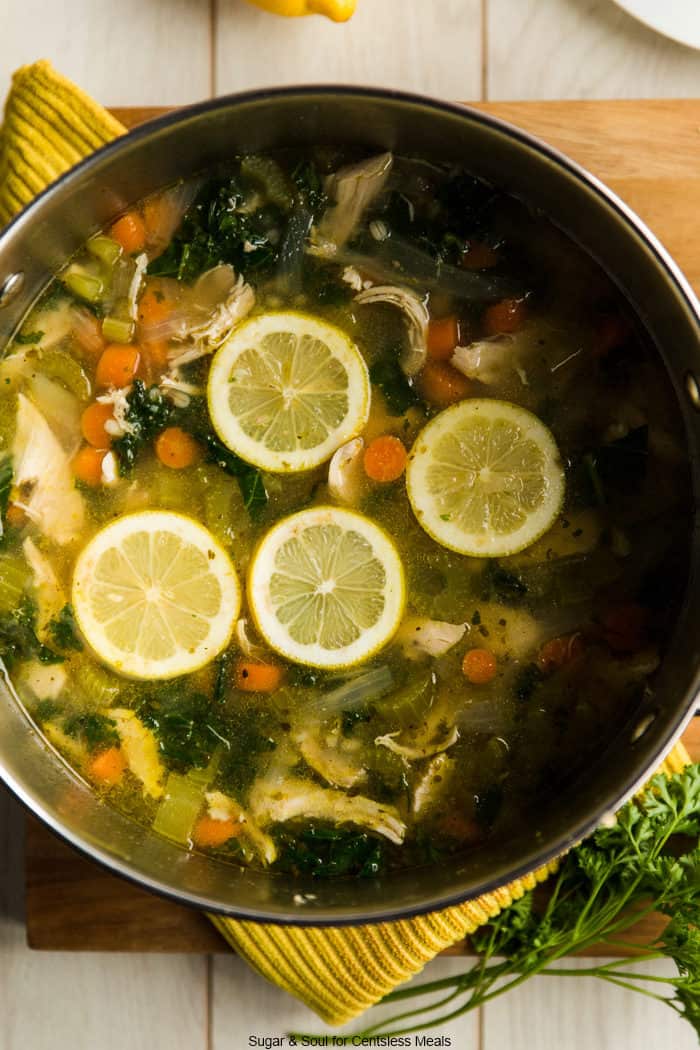 Chicken kale soup in a pot with lemon slices