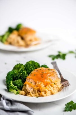 Crock-Pot Crock-Pot cheesy chicken rice on a white plate with broccoli and a fork