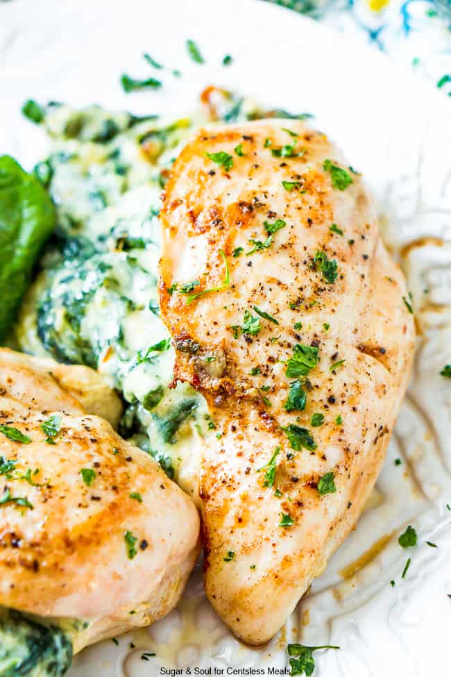 Spinach stuffed chicken on a plate garnished with parsley and Seasonings