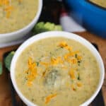 Broccoli Soup in white bowls garnished with shredded cheddar