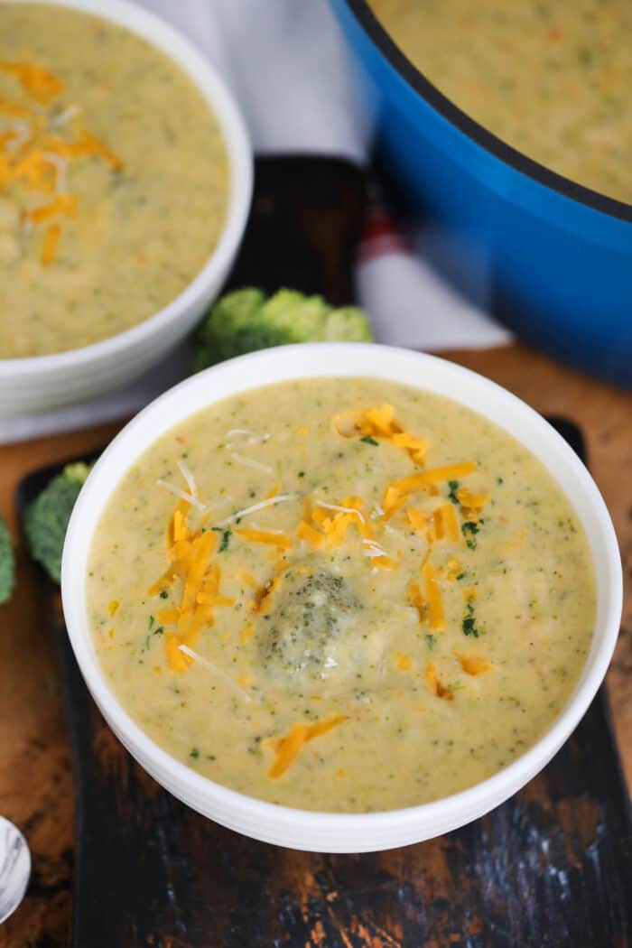 Broccoli Soup in white bowls garnished with shredded cheddar