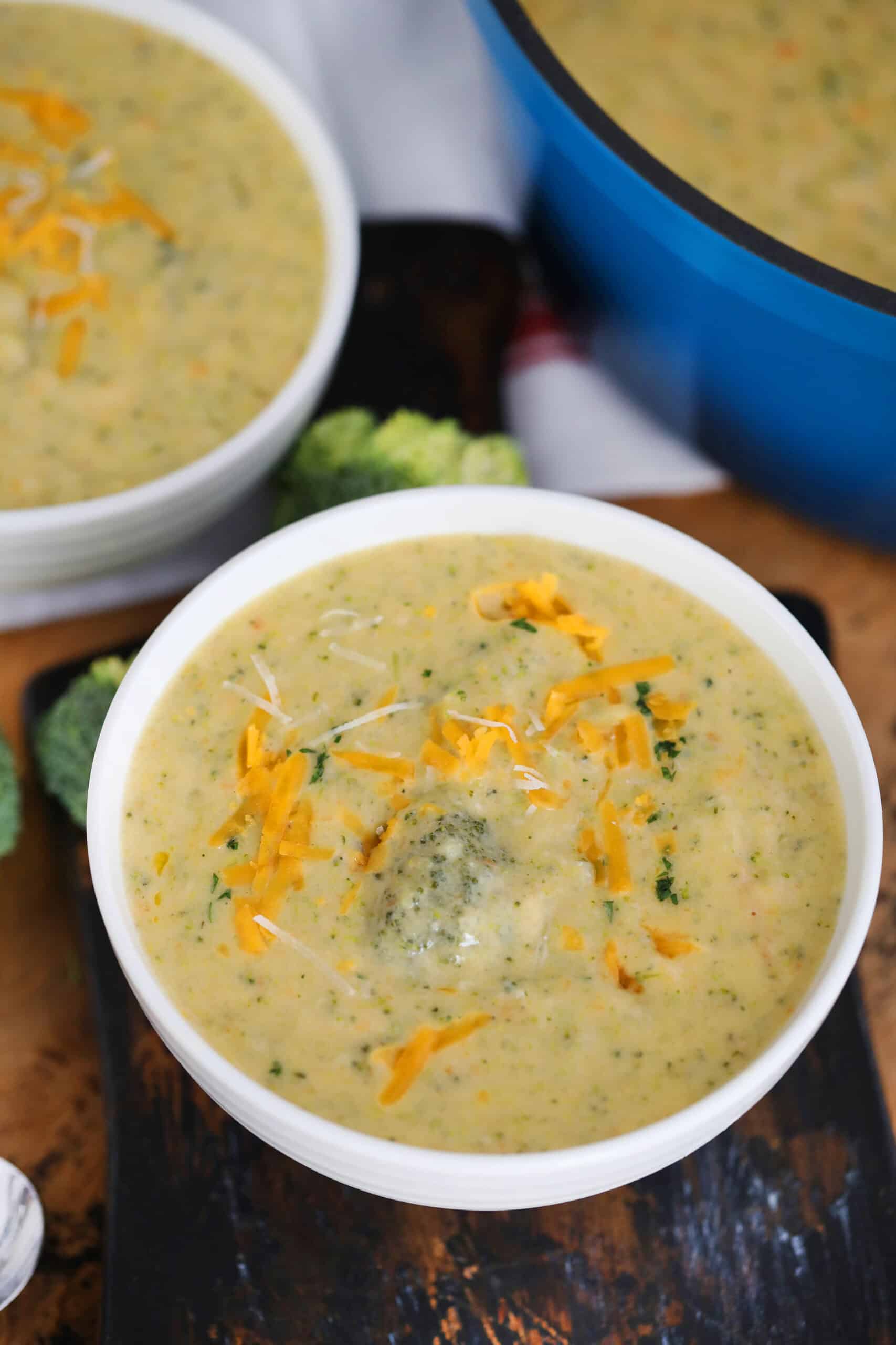 Broccoli Soup in white bowls garnished with shredded cheddar