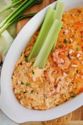 Shrimp dip in a white bowl with celery sticks and shrimp on top