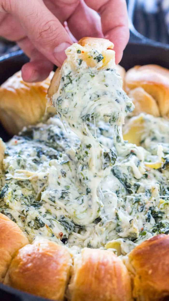 Spinach Artichoke Dip being dipped with a piece of bread