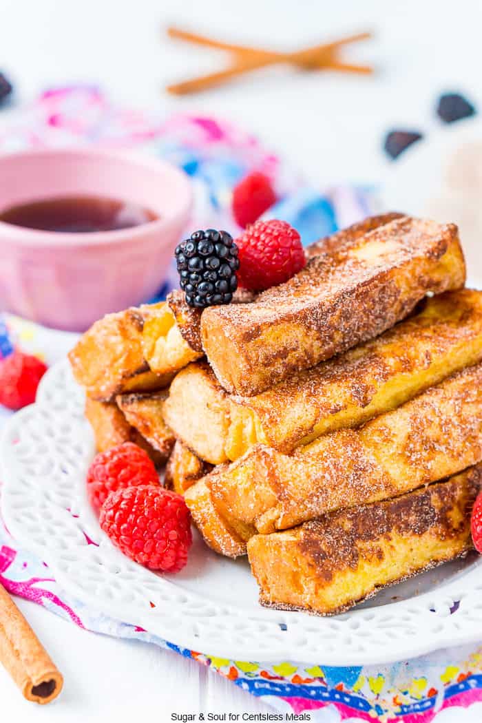 French toast sticks on a white plate with raspberries and blackberries