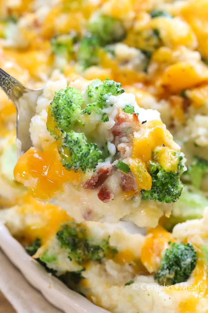 Broccoli potato casserole in a dish with a scoop on a spoon