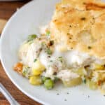 Chicken pot pie on a white plate with a fork and parsley
