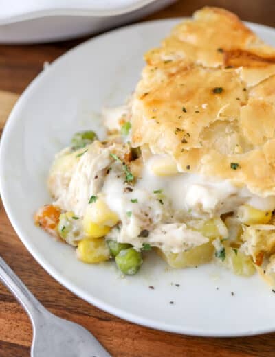 Chicken pot pie on a white plate with a fork and parsley