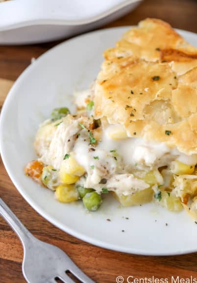 Chicken pot pie on a white plate with a fork and parsley