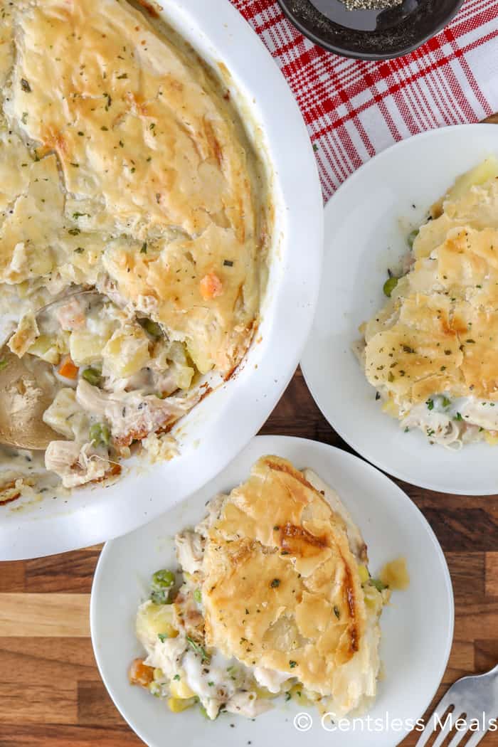 Chicken pot pie on two plates with a pie plate on the side