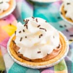 Mini No Bake Chocolate Cheesecake with whipped cream and chocolate sprinkles on a colorful checkered napkin.